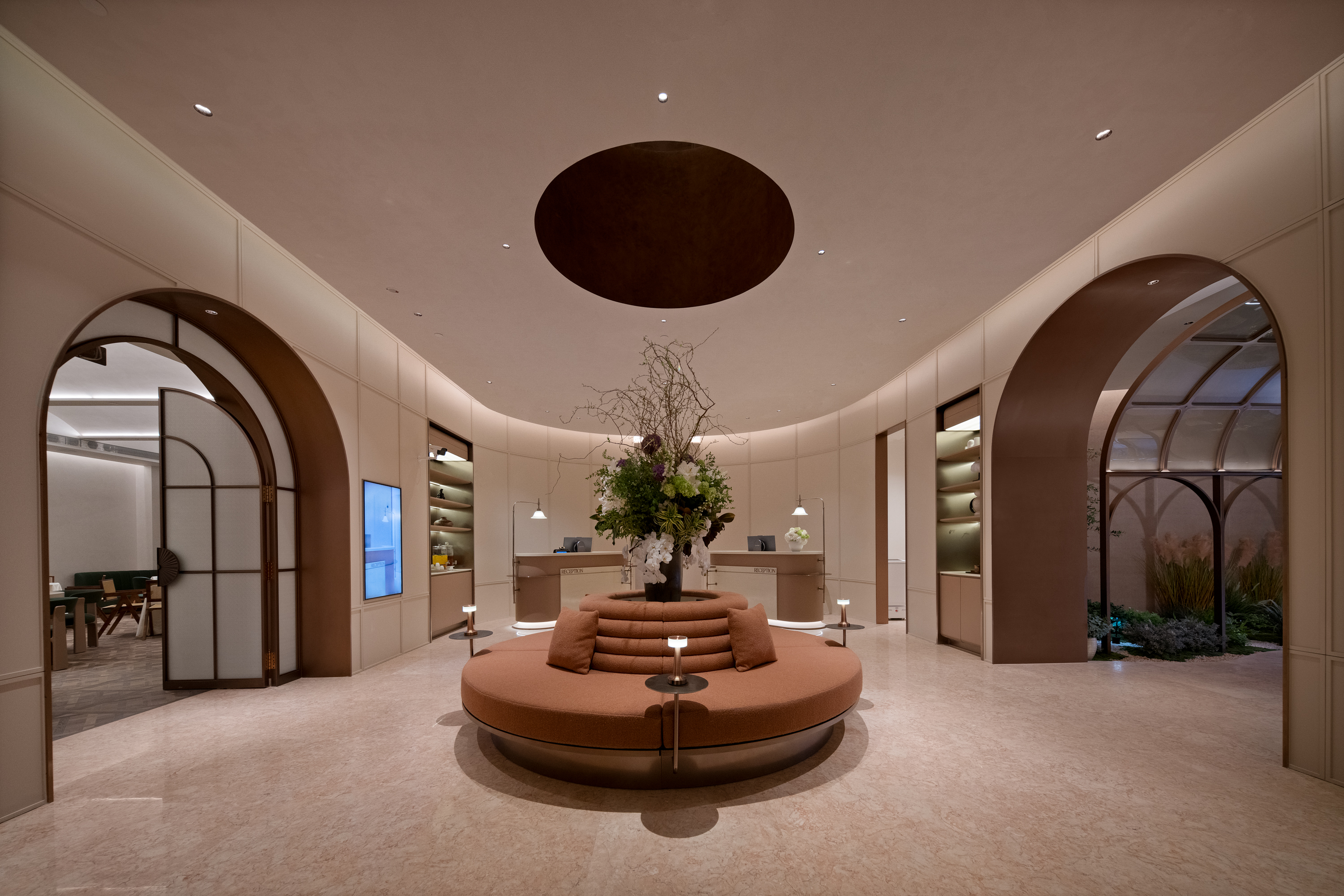 The domed arrival lounge at H+ Hotel, with bronze arches and a circular sofa